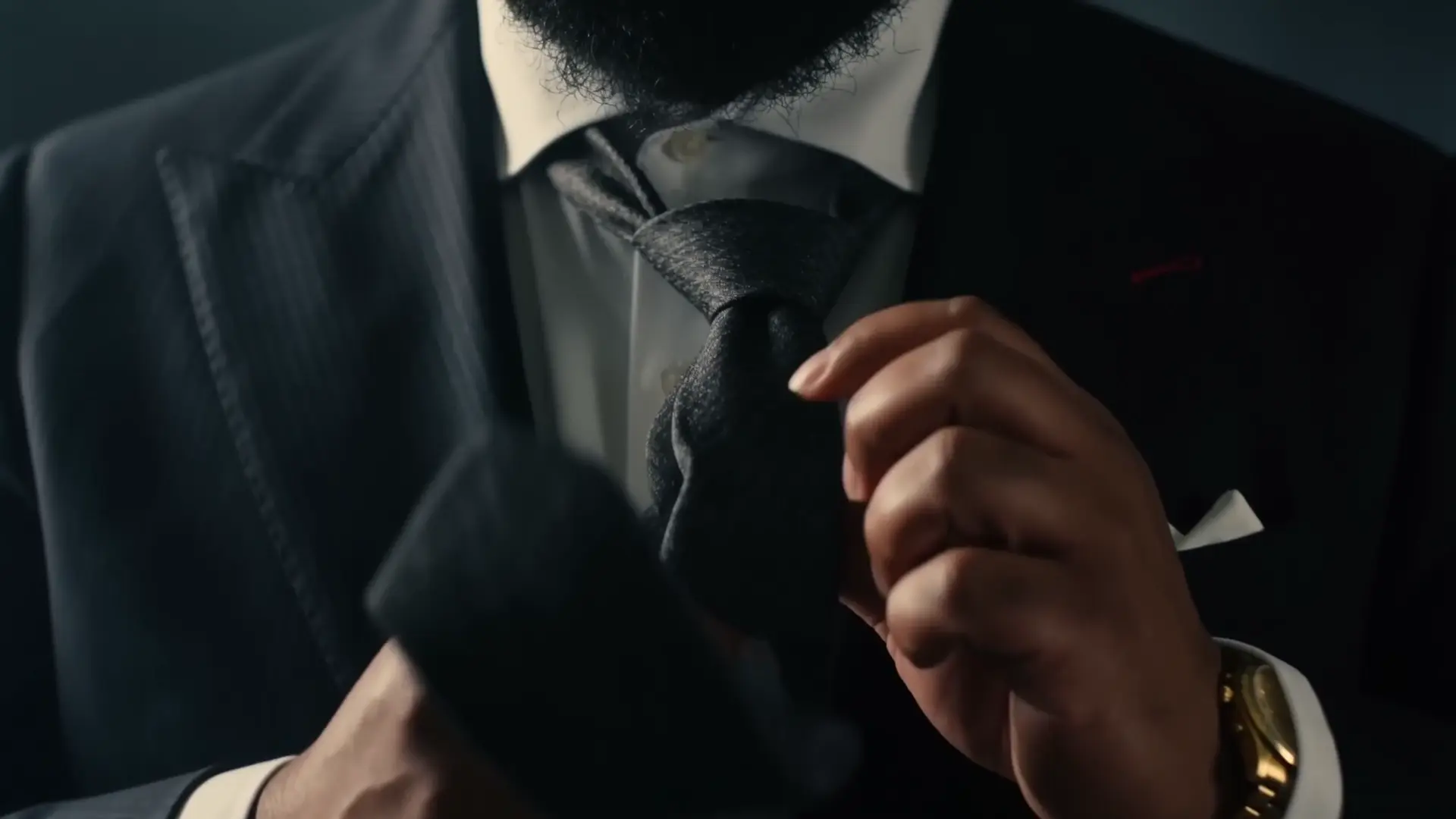 Close on Justin Redditt's hands adjusting the knot of a tie.